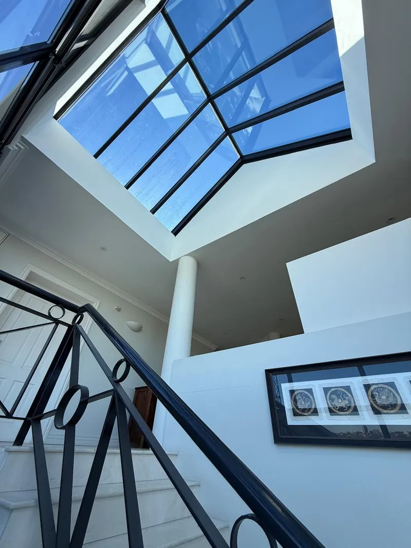 Stairwell under a large skylight with white walls and black balustrade